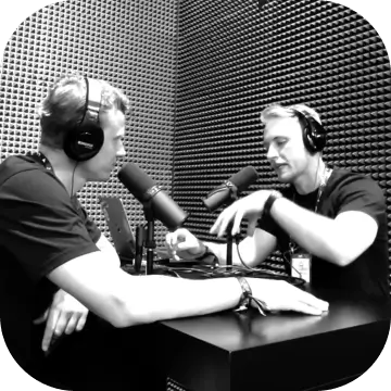 Two people having a conversation during a podcast interview session in a studio.